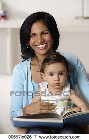 Stock Photo - woman flipping picture book with baby. Fotosearch