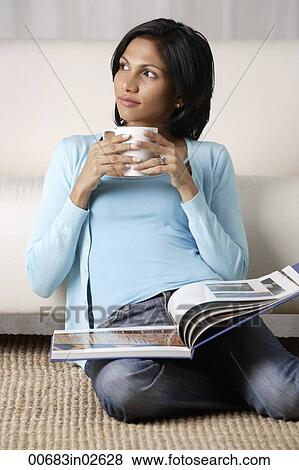 woman holding a mug, book on her lap View Large Photo Image Stock Photo - woman holding a mug, book on her lap. Fotosearch