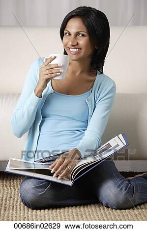 Stock Photo - woman holding a mug, book on her lap. Fotosearch