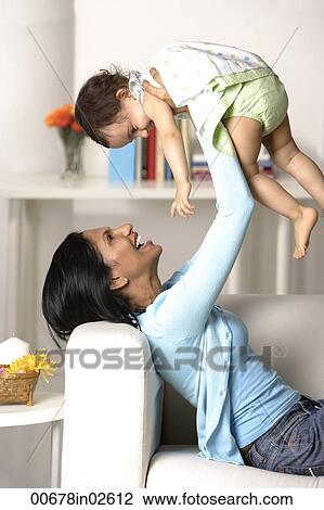 Stock Image - woman holding baby in the air. Fotosearch