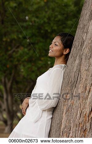 woman leaning on tree, looking away View Large Photo Image Stock Image - woman leaning on tree, looking away. Fotosearch