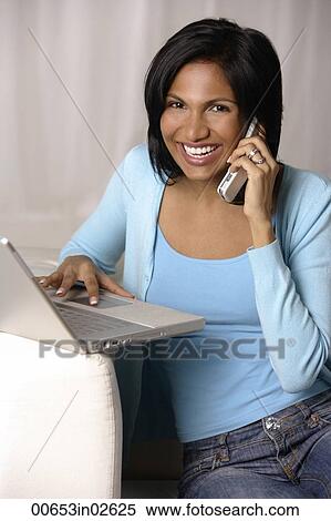woman sitting on couch using laptop and talking on mobile phone View Large Photo Image Stock Photography - woman sitting on couch using laptop and talking on mobile phone. Fotosearch