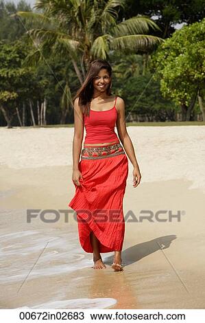 Stock Image - woman walking along the shore. Fotosearch