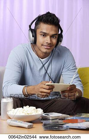 young man listening to music with headphones on View Large Photo Image Picture - young man listening to music with headphones on. Fotosearch