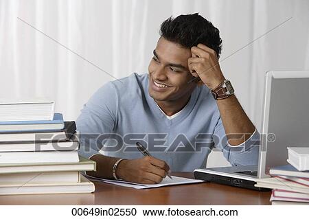 young man sitting at his desk, writing View Large Photo Image Stock Image - young man sitting at his desk, writing. Fotosearch