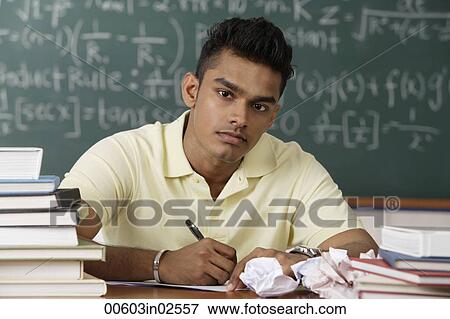 Stock Photo - young man sitting at his desk, writing. Fotosearch