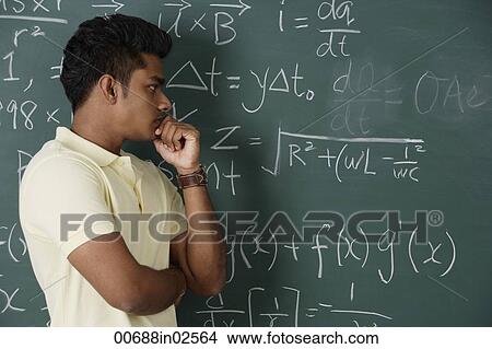Picture - young man standing in front of chalkboard, thinking. Fotosearch