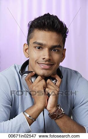 Stock Photo - young man with headphones around his neck, smiling at camera. Fotosearch