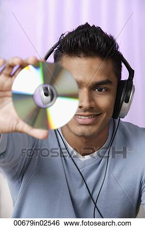 young man with headphones on, holding compact disc in front of him View Large Photo Image Stock Photograph - young man with headphones on, holding compact disc in front of him. Fotosearch
