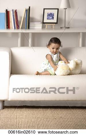 Stock Image - young toddler playing with soft toy on the couch. Fotosearch