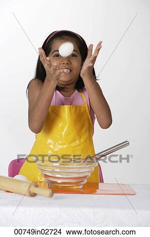 Picture - "Girl baking, tossing egg". Fotosearch