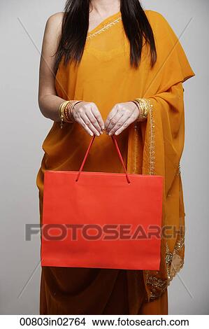 Cropped shot of woman wearing sari holding orange shopping bag View Large Photo Image Picture - Cropped shot of woman wearing sari holding orange shopping bag. Fotosearch