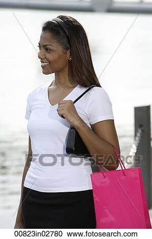 Stock Image - woman holding shopping bag out side. Fotosearch
