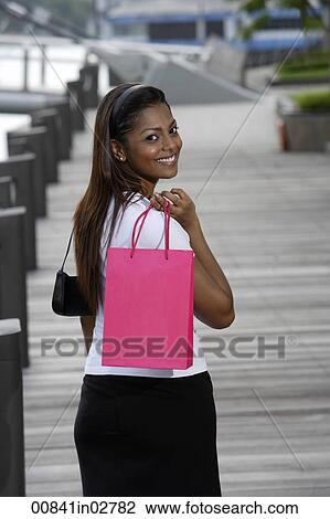woman walking outside holding shopping bag and smiling View Large Photo Image Stock Image - woman walking outside holding shopping bag and smiling. Fotosearch