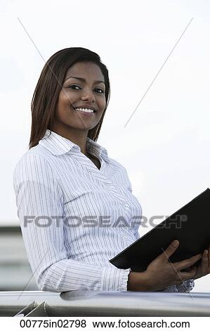 Young woman holding a folder outside View Large Photo Image Stock Photo - Young woman holding a folder outside. Fotosearch