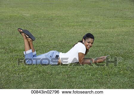 Young woman laying on grass listening to MP3 player View Large Photo Image Stock Photograph - Young woman laying on grass listening to MP3 player. Fotosearch