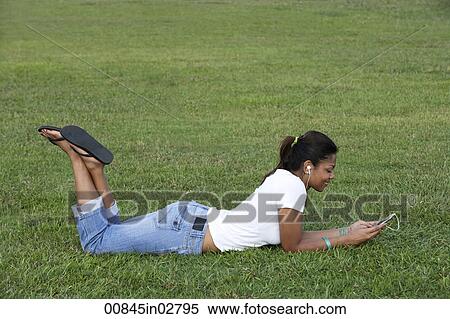 Young woman laying on grass listening to MP3 player View Large Photo Image Stock Photography - Young woman laying on grass listening to MP3 player. Fotosearch