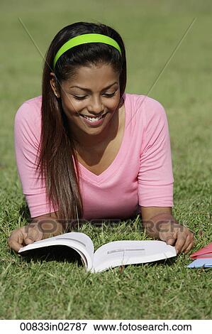 Young woman laying on grass reading a book View Large Photo Image Stock Photo - Young woman laying on grass reading a book. Fotosearch