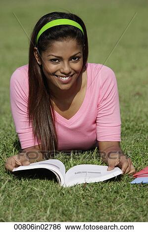 young woman laying on grass reading a book View Large Photo Image Stock Photograph - young woman laying on grass reading a book. Fotosearch
