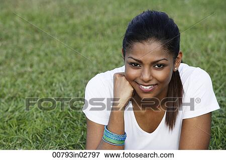 Stock Photo - young woman laying on grass, smiling. Fotosearch