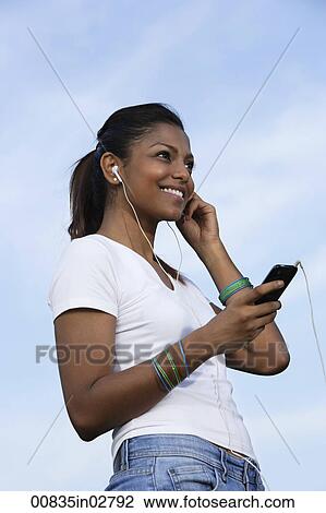 Young woman listening to a MP3 player. View Large Photo Image Stock Image - Young woman listening to a MP3 player.. Fotosearch