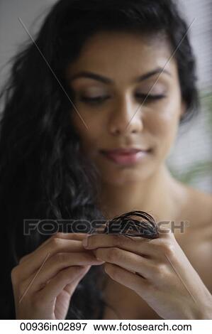 Stock Photo - close up of Indian woman looking at her hair.. Fotosearch