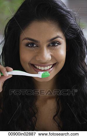 Stock Photo - Head shot of Indian woman brushing her teeth and smiling.. Fotosearch