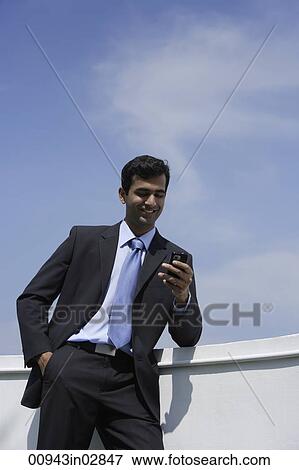 Stock Photo - Indian businessman reading text message outside.. Fotosearch