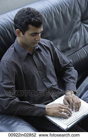 Indian businessman sitting on black sofa with laptop. View Large Photo Image Stock Image - Indian businessman sitting on black sofa with laptop.. Fotosearch