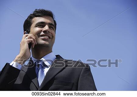 Indian businessman talking on phone outside. View Large Photo Image Picture - Indian businessman talking on phone outside.. Fotosearch