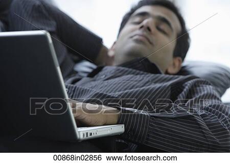 Indian man relaxing on sofa with laptop. View Large Photo Image Stock Photograph - Indian man relaxing on sofa with laptop.. Fotosearch