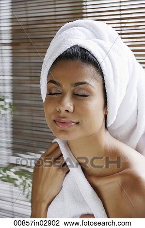 Stock Image - Indian woman closing her eyes relaxing with towel on her head. Fotosearch