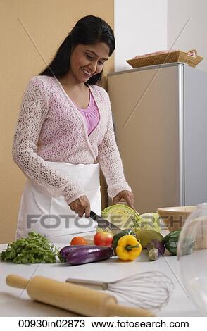 Indian woman cutting vegetables in the kitchen View Large Photo Image Stock Image - Indian woman cutting vegetables in the kitchen. Fotosearch