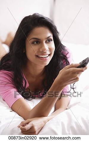 Indian woman laying on bed watching TV View Large Photo Image Stock Image - Indian woman laying on bed watching TV. Fotosearch
