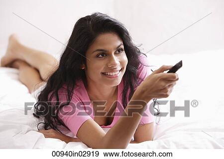 Indian woman laying on bed watching TV View Large Photo Image Stock Photo - Indian woman laying on bed watching TV. Fotosearch