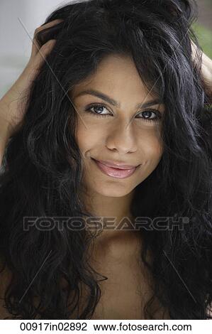 Stock Image - Indian woman playing with hair smiling.. Fotosearch