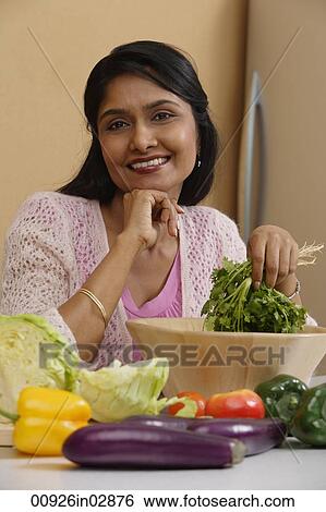 Indian woman smiling while preparing food View Large Photo Image Stock Photograph - Indian woman smiling while preparing food. Fotosearch