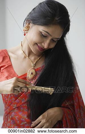 Stock Image - Indian woman wearing a sari and combing her hair. Fotosearch
