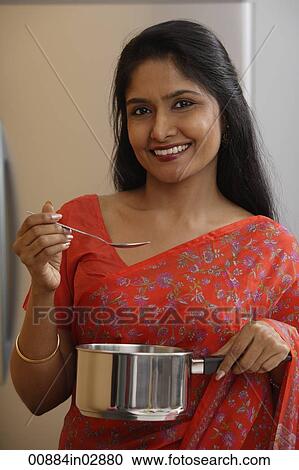 Stock Image - Indian woman wearing sari while preparing food.. Fotosearch