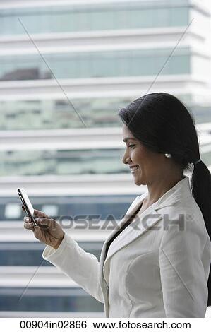 Profile of Indian woman looking at phone outside. View Large Photo Image Stock Photograph - Profile of Indian woman looking at phone outside.. Fotosearch