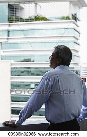 Back shot of Indian man looking at building View Large Photo Image Stock Photograph - Back shot of Indian man looking at building. Fotosearch