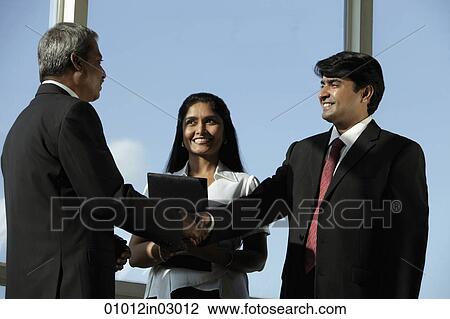Business men shaking hands while female colleague looks on. View Large Photo Image Stock Image - Business men shaking hands while female colleague looks on.. Fotosearch