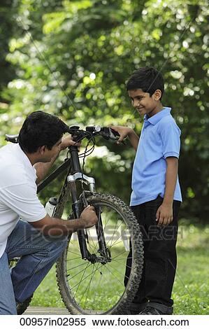 Father and son fixing bike together View Large Photo Image Stock Photography - Father and son fixing bike together. Fotosearch