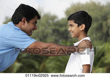 Father and son looking at each other and smiling outdoors. View Large Photo Image Stock Photography - Father and son looking at each other and smiling outdoors.. Fotosearch