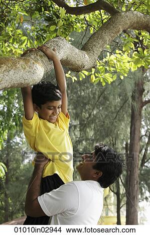 Father helping his son climb a tree View Large Photo Image Picture - Father helping his son climb a tree. Fotosearch