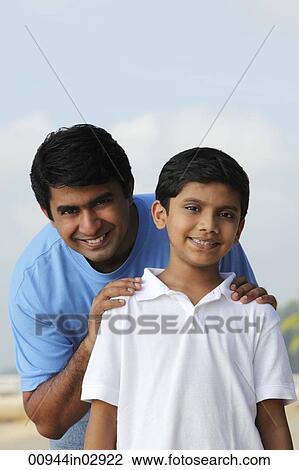 Stock Image - Father holding sons shoulders and smiling. Fotosearch