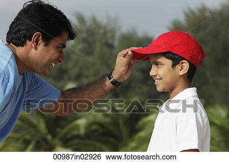 Father putting on son's baseball cap. View Large Photo Image Stock Photograph - Father putting on son's baseball cap.. Fotosearch