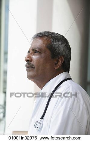 Head shot of Indian doctor looking up and thinking View Large Photo Image Stock Photograph - Head shot of Indian doctor looking up and thinking. Fotosearch