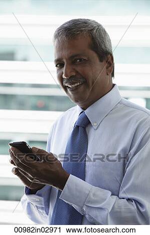 Head shot of mature Indian man holding hand phone View Large Photo Image Stock Image - Head shot of mature Indian man holding hand phone. Fotosearch