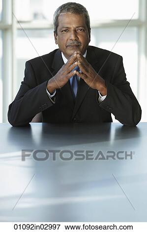 Indian business man sitting at table View Large Photo Image Stock Photo - Indian business man sitting at table. Fotosearch